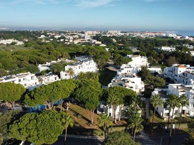 Übersicht einer Ferienanlage mit weiß getünchten Gebäuden und viel Grün umgeben von Bäumen.