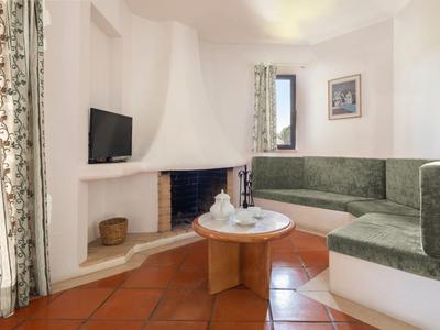 Gemütliche Sitzecke mit grünem Ecksofa, Kamin und Flachbildfernseher in einem hellen Raum.