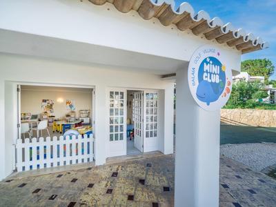 Außenansicht eines kleinen Cafés mit weißem Zaun und Schild an der Säule.
