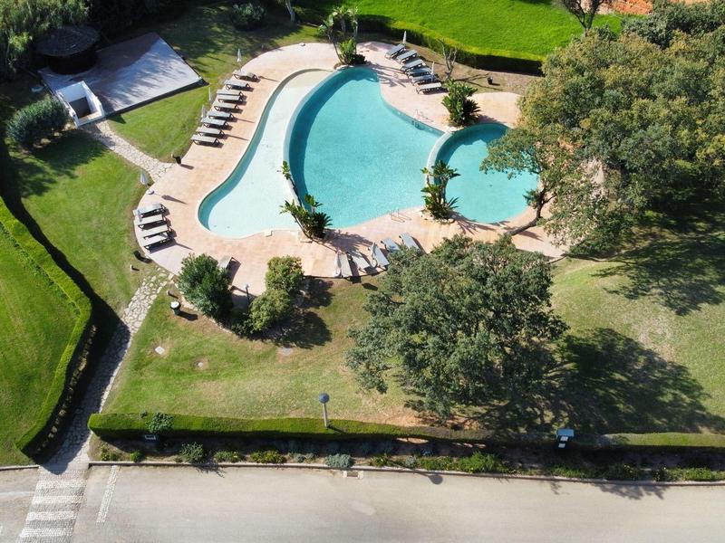 Luftaufnahme eines schwimmbadbereichs mit Liegestühlen und grünen Wiesen in einem Hotel