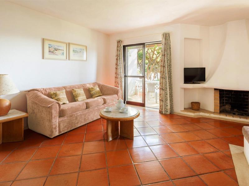 Gemütliches Wohnzimmer mit Sofa, Kamin und Zugang zum Balkon in einem Ferienhaus.