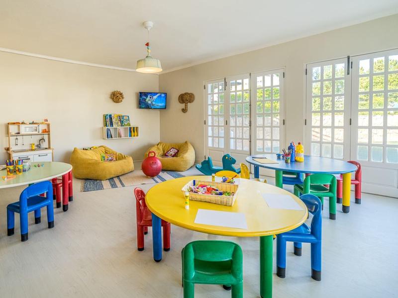 Heller, freundlicher Spielraum mit bunten Kindertischen und Stühlen sowie gemütlichen Sitzgelegenheiten.