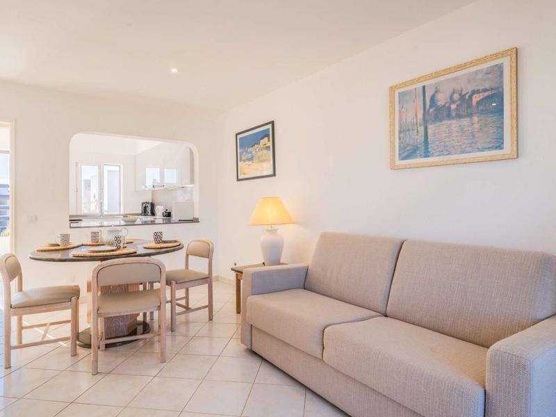 Helles Wohnzimmer mit beigem Sofa, Esstisch aus Holz und Kunstwerken an der Wand.