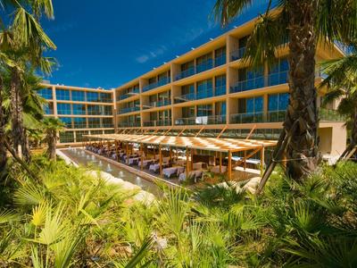 Helles Wohnzimmer mit moderner Einrichtung, blauen Sesseln, grauem Sofa und großem Fenster.