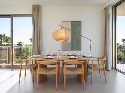 Moderner Essbereich mit Holzstühlen, großem Tisch, Hängelampe und bodentiefen Fenstern mit Blick ins Grüne.