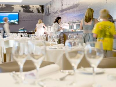 Ein elegantes Restaurant mit weißgedeckten Tischen und mehreren Gästen im Hintergrund.