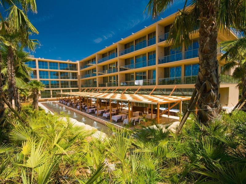 Helles Wohnzimmer mit moderner Einrichtung, blauen Sesseln, grauem Sofa und großem Fenster.