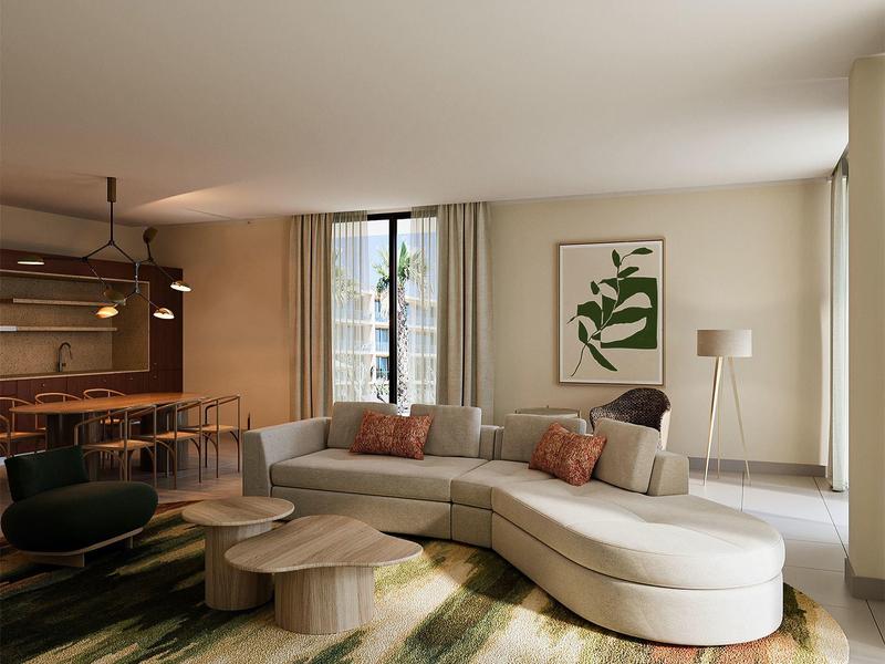 Moderner Wohnraum mit geschwungener hellbeiger Couch, grünem Teppich und großem Fenster mit Gardinen.