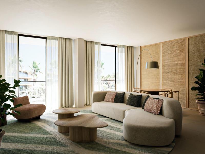 Helles Wohnzimmer mit runden Möbeln, grünem Teppich und großen Fenstern mit weißen Vorhängen.