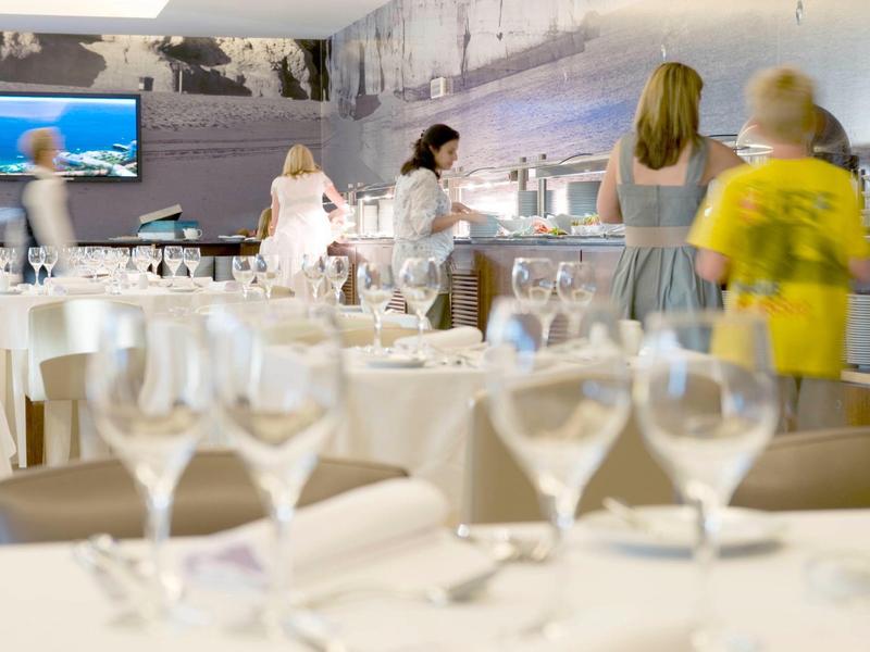 Ein elegantes Restaurant mit weißgedeckten Tischen und mehreren Gästen im Hintergrund.