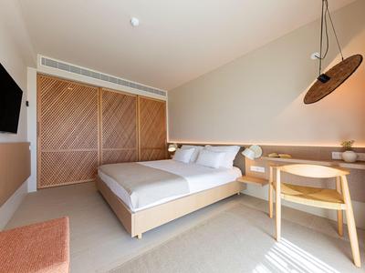 Modernes Hotelzimmer mit Doppelbett, Holzmöbeln und einem großen Wandfernseher.