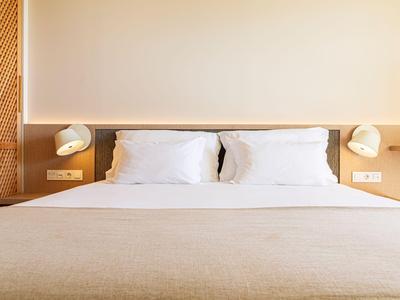 Modernes Hotelzimmer mit Doppelbett und minimalistischer Beleuchtung an beiden Seiten.