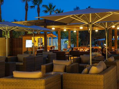 Gemütliche Lounge mit Sofa-Sitzgelegenheiten und Sonnenschirmen in einem Hotel bei Abenddämmerung.