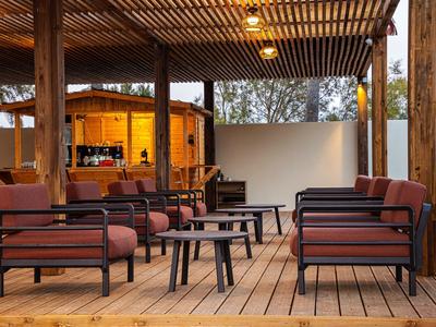 Freiluftlounge mit modernen Sesseln und Tischen auf Holzterrasse eines Hotels.