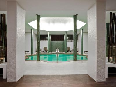 Moderner Innenpool mit Säulen und bequemen Liegestühlen in einem Hotel.