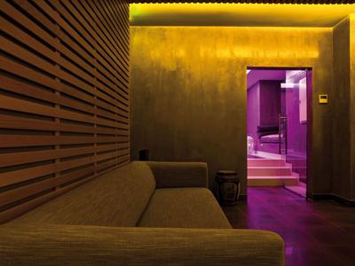 Modern eingerichteter Hotel-Warteraum mit brauner Couch und lila beleuchtetem Flur.