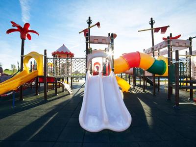 Barevné dětské hřiště s klouzačkami a lezeckými konstrukcemi pod jasnou oblohou.