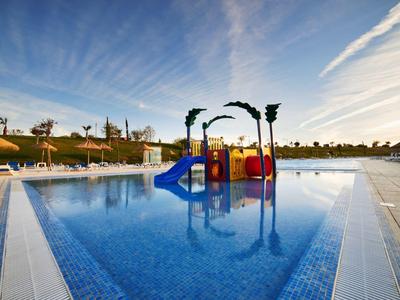 Barevné vodní hřiště v bazénu u letoviska pod jasnou oblohou.