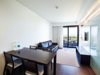 Světý obývací pokoj s jídelním stolem, koženou pohovkou a přístupem na balkon s výhledem.