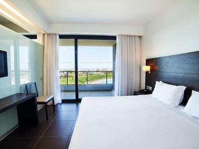 Moderní hotelový pokoj s velkou postelí a balkónovými dveřmi s výhledem na kanál.