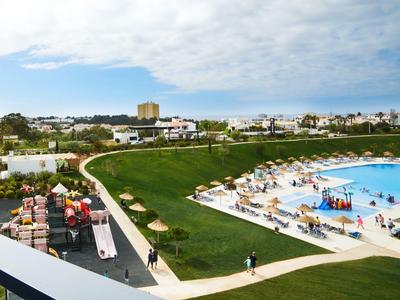 Pohled na hotel s bazénem, skluzavkami a lehátky v slunečný den