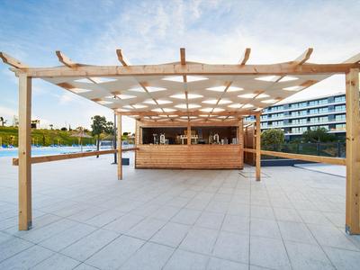 Moderní dřevěný pavilon u bazénu na prostorné dlažbě vedle hotelového bazénu.