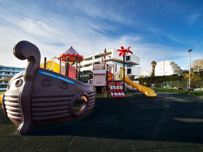 Moderní dětské hřiště s pirátskou lodí a skluzavkami v hotelové zahradě.