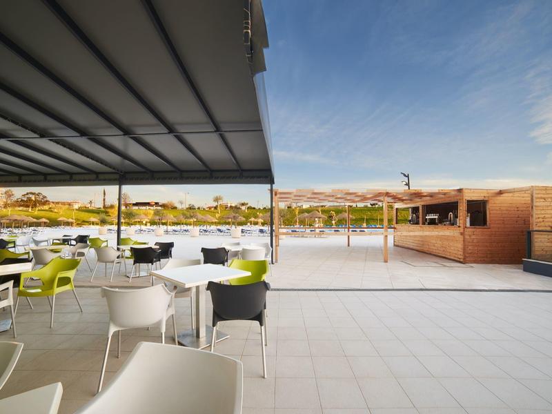 Venkovní restaurace s bílými židlemi s výhledem na řeku za jasné oblohy