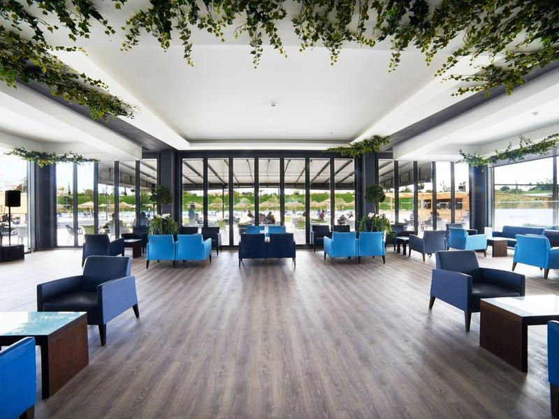 Prostorná světlá jídelna s modrými a tmavými židlemi a spoustou přirozeného světla.