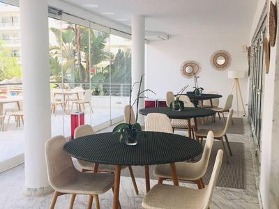 Moderner Wintergarten mit Marmorboden, schwarzem Tisch und bequemen Stühlen in hellem Ambiente.