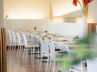 Heller, moderner Speiseraum mit weißen Stühlen, Holzboden und roter Blume als Dekoration.