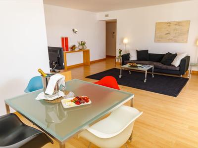 Heller Wohnraum mit Holzboden, Essbereich, bunten Stühlen und Sofa, minimalistischem Design.