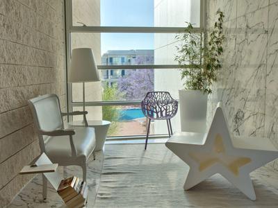 Gemütlicher Balkon mit weißen Stühlen, großer Stern-Dekoration, Pflanze und Blick auf Stadt.