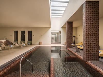 Piscine intérieure moderne avec chaises longues dans un espace bien-être élégant.