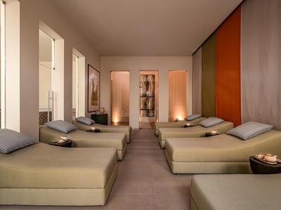 Salle de détente avec plusieurs chaises longues, lumière tamisée et tons chauds.