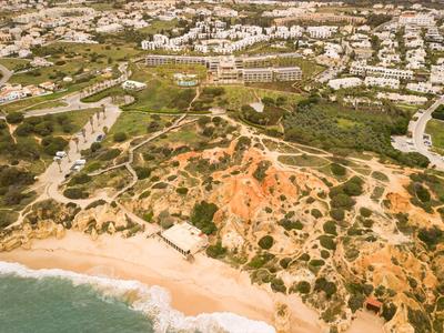 Vue aérienne d'une plage avec des falaises rouges et un village en arrière-plan.