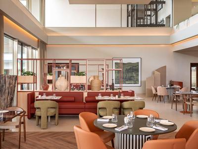 Espace restaurant d'hôtel lumineux et moderne avec sièges confortables et tables élégamment dressées.