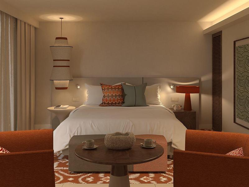 Chambre d'hôtel moderne avec grand lit, fauteuils orange et table basse ronde.