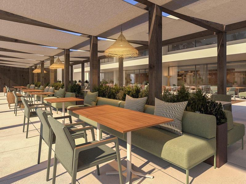 Espace extérieur d'un hôtel avec une zone couverte et des tables et chaises modernes.