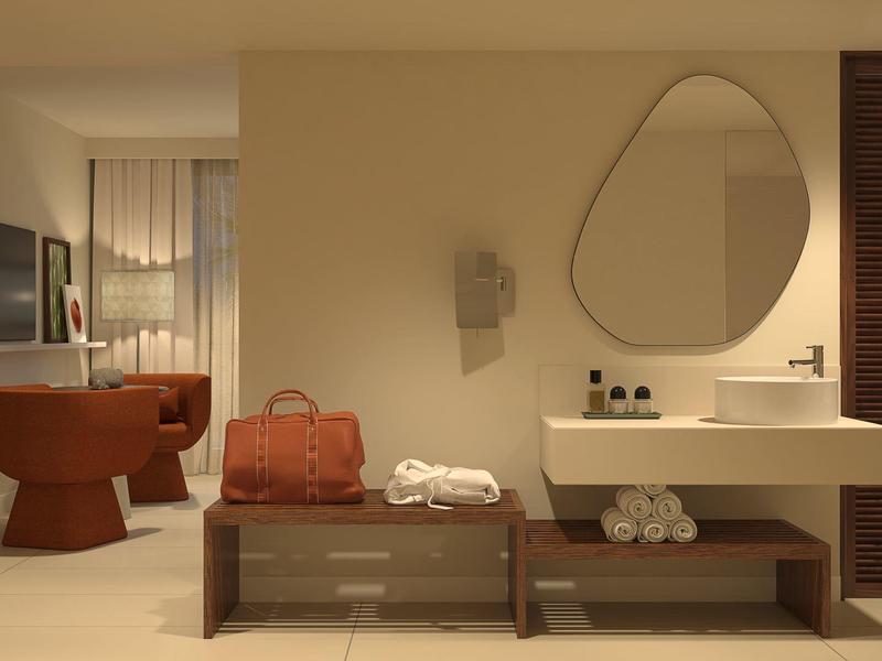 Chambre d'hôtel moderne avec coin salon et miroir sous une lumière chaude.