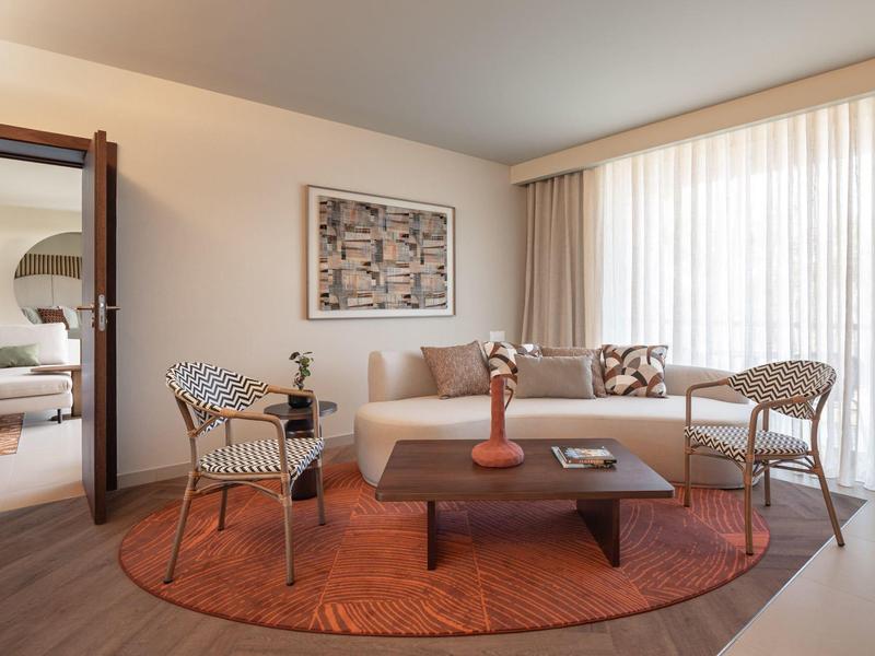 Séjour confortable à l'hôtel avec canapé, fauteuils et accents de couleurs chaudes dans le salon.