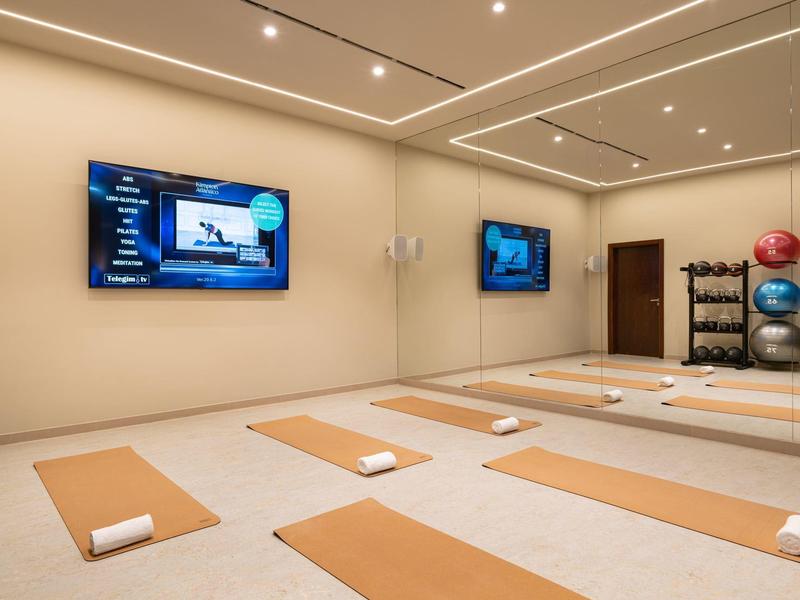 Espace bien-être moderne avec tapis de yoga, serviettes et écrans muraux.