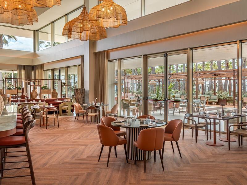 Restaurant lumineux avec mobilier moderne et grandes fenêtres donnant sur l'extérieur.