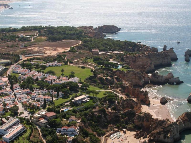 Panorama costiero con rocce, spiagge, hotel e aree verdi lungo la costa.