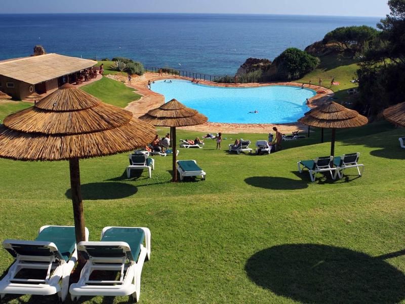 Vista di una piscina con lettini e ombrelloni vicino al mare in una giornata di sole