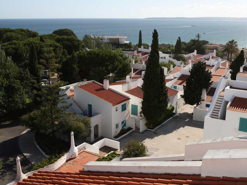 Vista di un villaggio costiero bianco con tetti rossi e mare blu sullo sfondo.