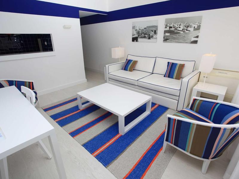 Soggiorno moderno con divano, poltrona, tappeto e due quadri sulla parete.