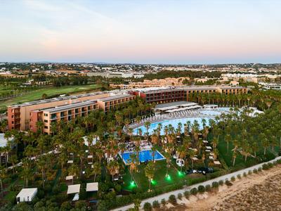 Großes Hotelresort mit mehreren Gebäuden, Pool und Palmen in sonniger Umgebung.