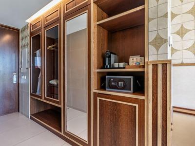 Hotelzimmer mit holzgetäfeltem Schrank, Spiegeln, Safe und Kaffeemaschine in Ablagefächern.