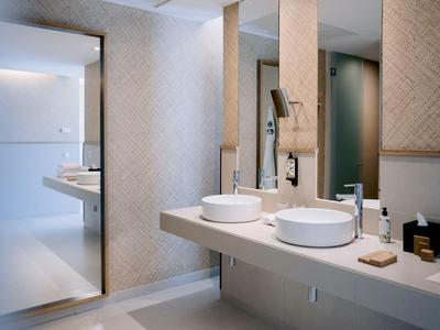 Modernes Hotelbad mit Doppelwaschbecken und spiegelnder Wandgestaltung.